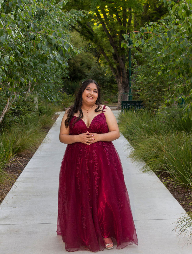 Myla in a burgundy formal dress on a concrete path