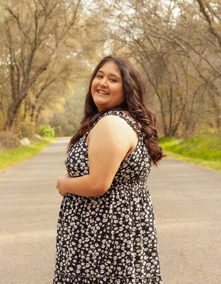 Myla in a black and white floral dress on a path